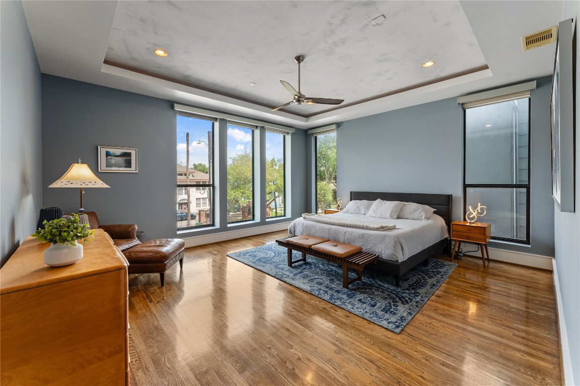 917 Peden Street Houston, TX 77006 - Photo 21 of 50 A spacious and tranquil primary suite with expansive windows and elegant finishes. Automatic room-darkening shades enhance comfort and privacy, creating a true retreat. Rich wood flooring adds warmth and sophistication throughout the space.
