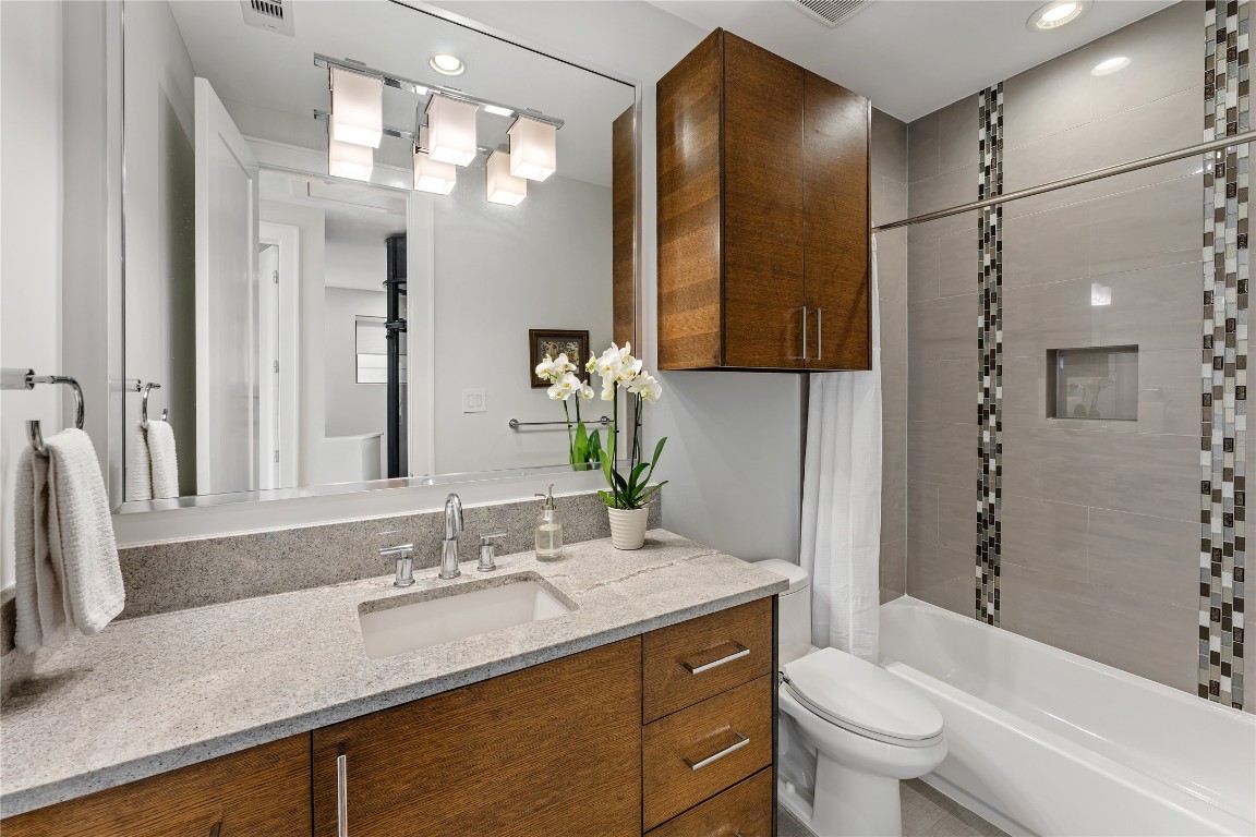 917 Peden Street Houston, TX 77006 - Photo 47 of 50 A beautifully finished bathroom with granite countertops, custom cabinetry, and modern fixtures. Designer tile accents and a clean, contemporary palette create a polished look. Natural light enhances the space, adding warmth and brightness.