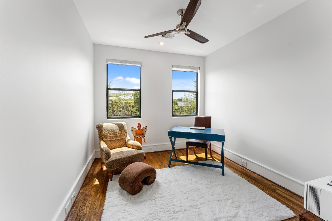 917 Peden Street Houston, TX 77006 - Photo 48 of 50 A bright and versatile full-size bedroom currently styled as a home office, complete with a walk-in closet. Large windows fill the space with natural light, while warm wood flooring adds character and charm. Easily adaptable to suit your needs, whether as a bedroom, office, or creative retreat.