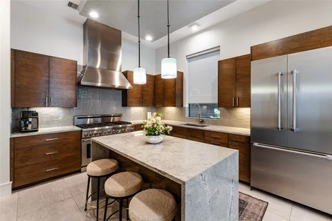 a kitchen with stainless steel appliances granite countertop a refrigerator a stove and a sink