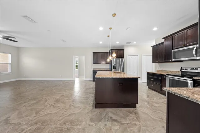 a kitchen with stainless steel appliances kitchen island granite countertop a sink and a refrigerator