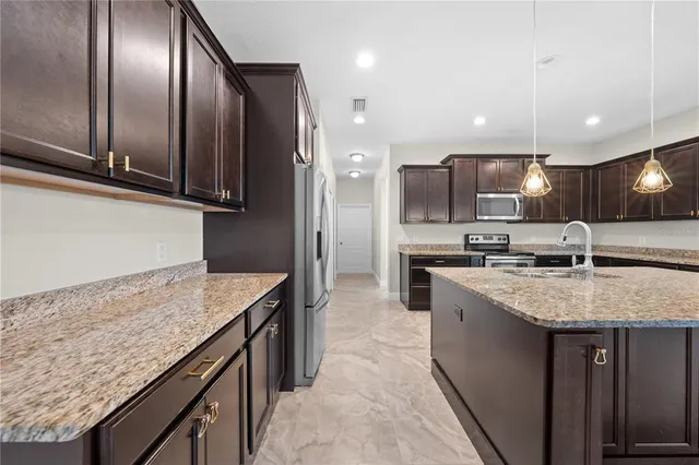 a kitchen with stainless steel appliances granite countertop a refrigerator a sink a stove and oven