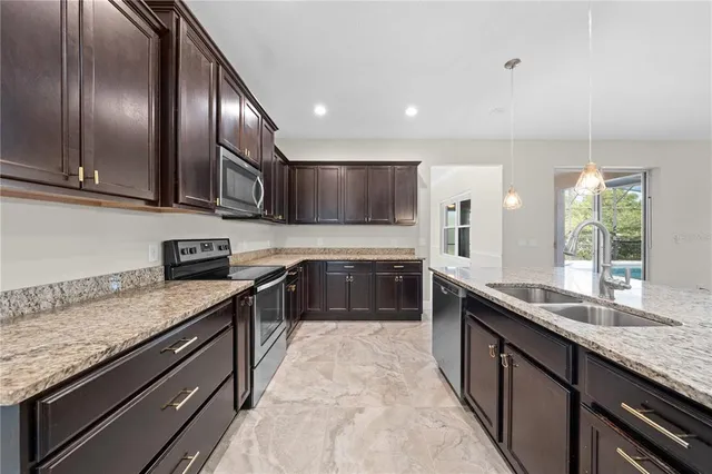 a kitchen with stainless steel appliances granite countertop a sink stove microwave and refrigerator