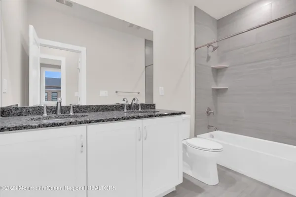 a bathroom with a granite countertop sink toilet and a mirror