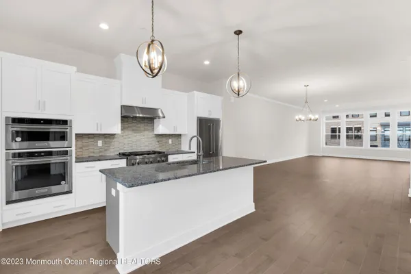a kitchen with stainless steel appliances granite countertop a stove a sink and a wooden floors
