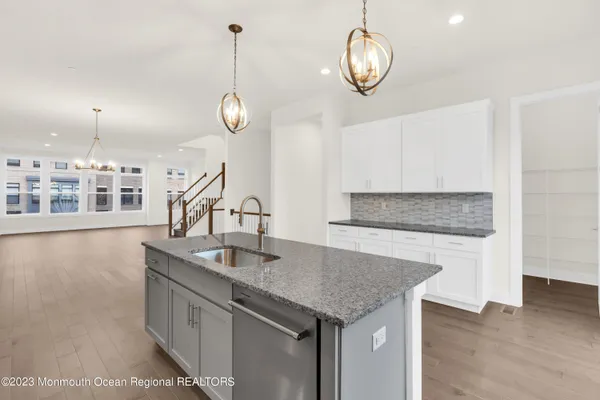 a kitchen with granite countertop a stove a kitchen island a chandelier and wooden floors