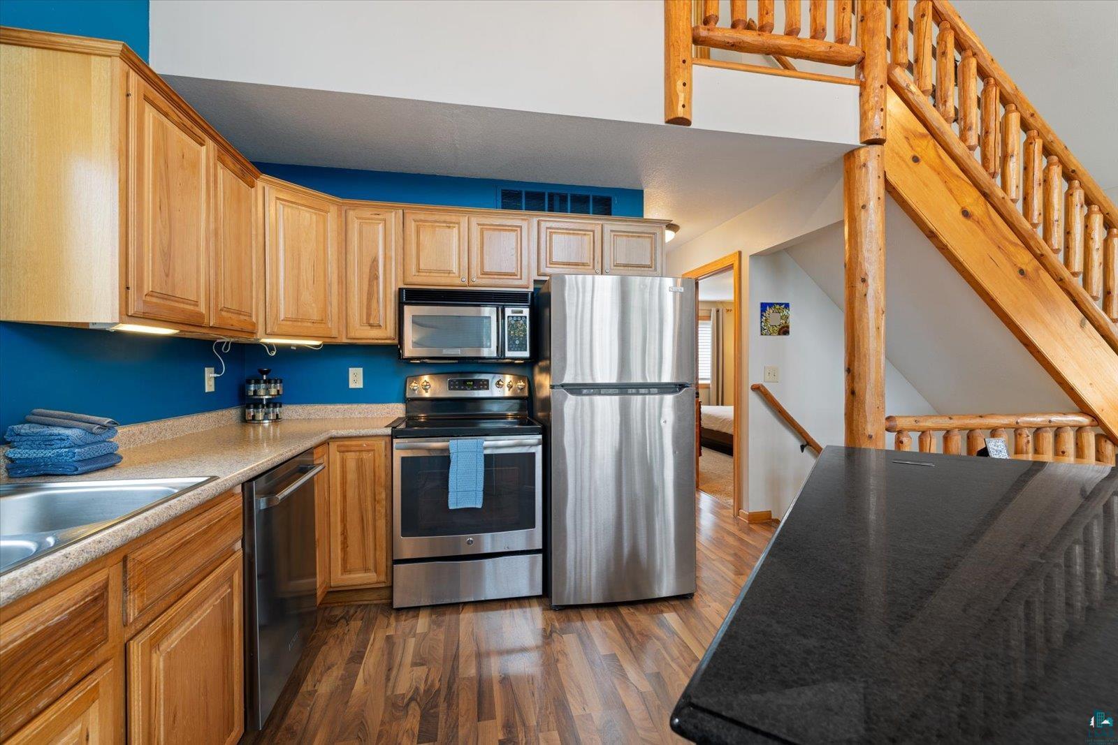 6266 Giants Ridge Road Biwabik, MN 55705 - Photo 5 of 37 Kitchen featuring wood cabinetry, stainless steel appliances, speckled countertops, and wood-finish flooring