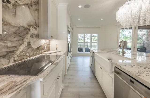 a large white kitchen with granite countertop a sink and dishwasher a stove with wooden floor