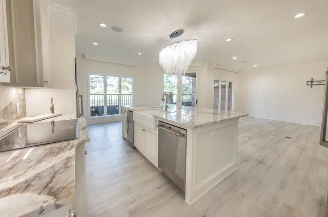 a large kitchen with granite countertop a large counter top a sink stainless steel appliances and cabinets