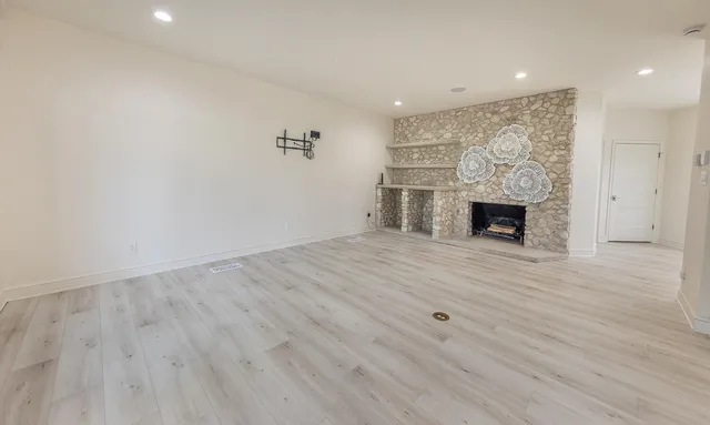 a view of empty room with wooden floor and fireplace