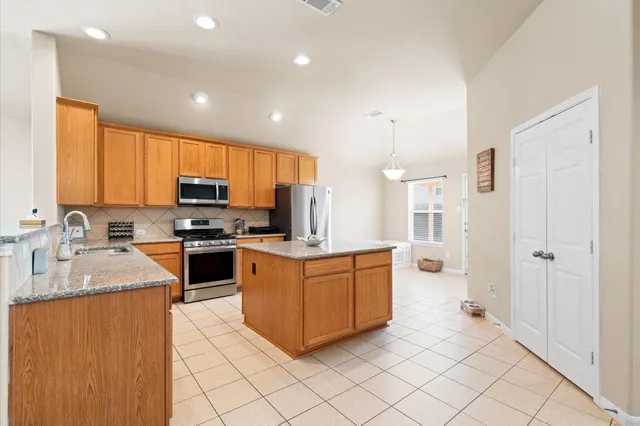 a kitchen with stainless steel appliances granite countertop a stove top oven a sink dishwasher a refrigerator and a granite counter tops with white cabinets