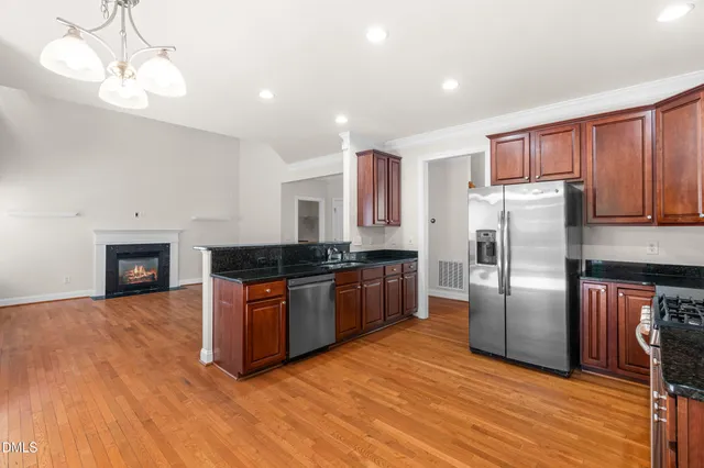 a kitchen with stainless steel appliances granite countertop a refrigerator a sink dishwasher a stove with wooden floors