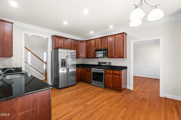 a kitchen with stainless steel appliances granite countertop a refrigerator a sink dishwasher a stove and white countertops with wooden floor