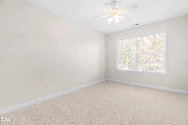 an empty room with a window and a fan