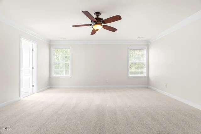 an empty room with ceiling fan and windows