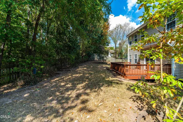 a backyard of a house with large trees and plants