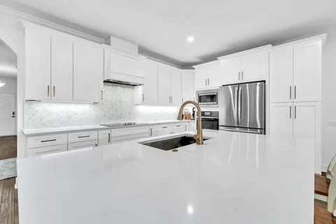 a kitchen with stainless steel appliances a dining table chairs and wooden floor