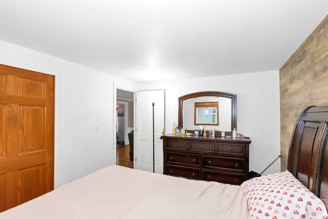 a bedroom with a bed and dresser with mirror