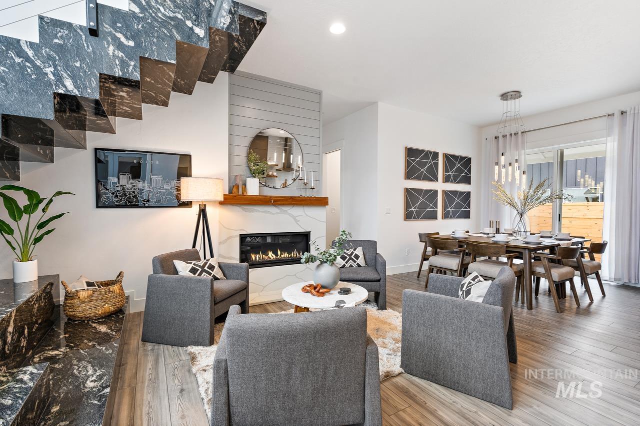 599 West Warren Street Boise, ID 83706 - Photo 4 of 41 Open-concept main level featuring wood-finish flooring, a contemporary fireplace with a stone surround and wood mantel, a floating staircase with dark stone treads, and a dining area with a modern chandelier