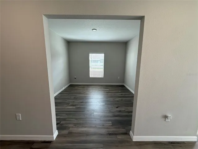 a view of empty room with window and wooden floor