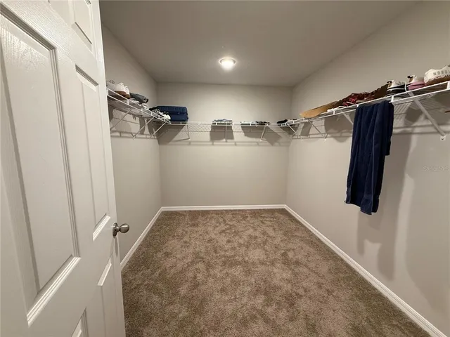 a view of walk in closet with clothes and shoes