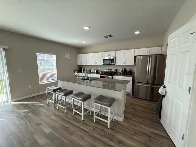 a kitchen with stainless steel appliances granite countertop a table chairs sink refrigerator and microwave