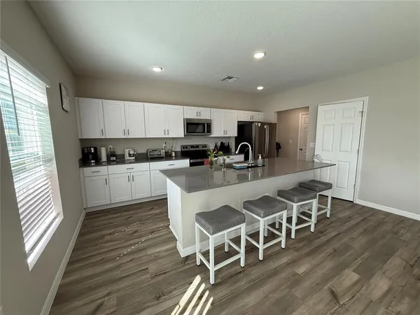 a kitchen with stainless steel appliances granite countertop a refrigerator sink and white cabinets