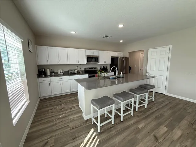 a kitchen with stainless steel appliances granite countertop a refrigerator sink and white cabinets