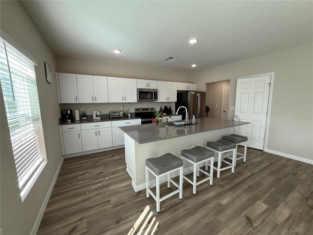 3464 Dahlia Drive Haines City, FL 33844 - Photo 38 of 41 a kitchen with stainless steel appliances granite countertop a table chairs sink refrigerator and microwave