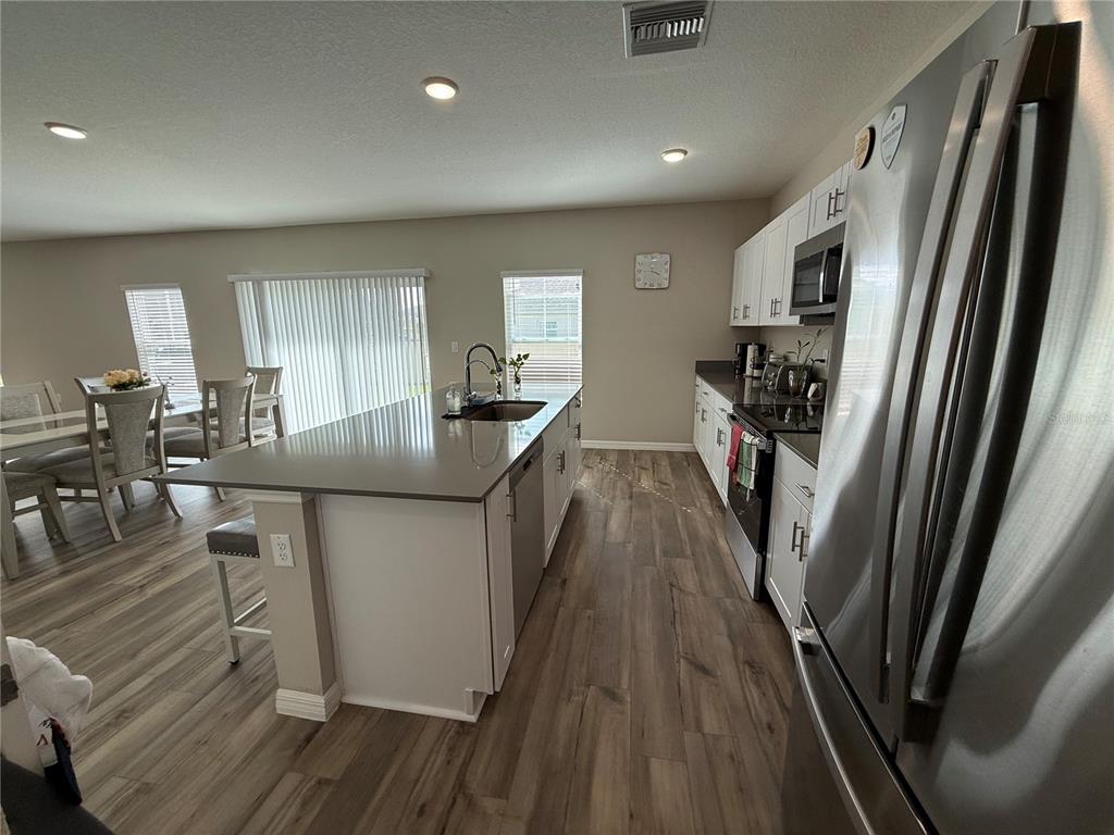 3464 Dahlia Drive Haines City, FL 33844 - Photo 41 of 41 a kitchen with stainless steel appliances a refrigerator a stove a sink dishwasher and white cabinets with wooden floor