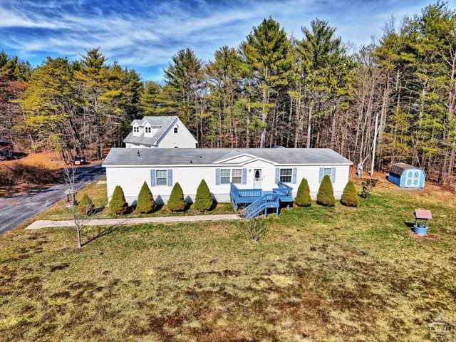 an aerial view of a house with large trees and wooden fence