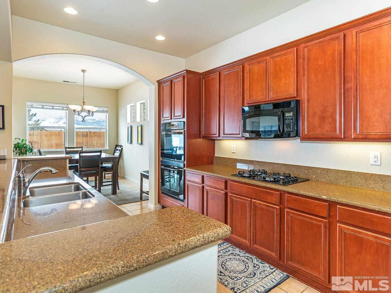 10175 Gold Mine Drive Reno, NV 89521 - Photo 10 of 24 a kitchen with stainless steel appliances granite countertop wooden cabinets a stove a sink and a large window