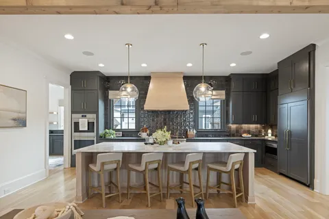 a dining room with wooden floor a chandelier a glass table and chairs