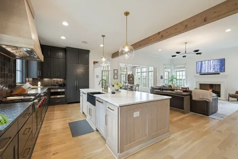 a dining room with wooden floor a chandelier a wooden table and chairs