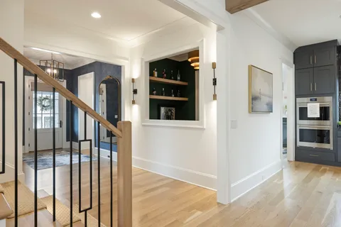 a view of a hallway to a livingroom with wooden floor and furniture