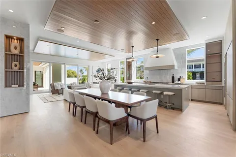 a large dining hall with stainless steel appliances kitchen island granite countertop a table chairs in it and a window