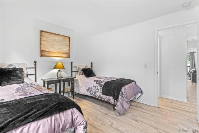 a bedroom with a bed a dresser and wooden floor