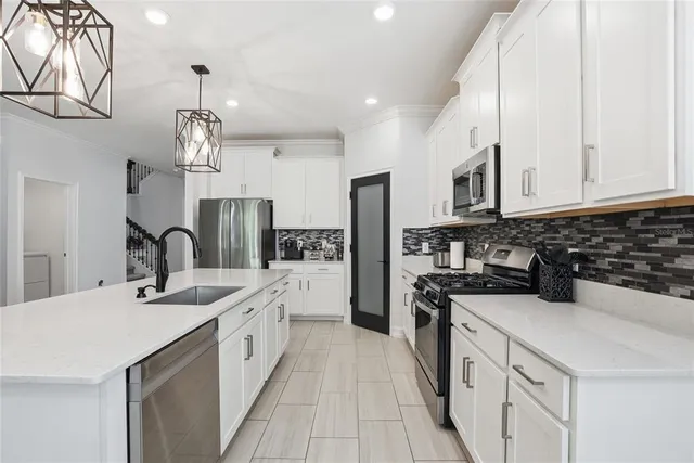 a kitchen with stainless steel appliances a sink dishwasher a refrigerator a stove top oven a counter space and cabinets