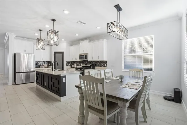 a kitchen with stainless steel appliances granite countertop a stove a refrigerator a kitchen island a sink dishwasher a dining table and chairs with wooden floor