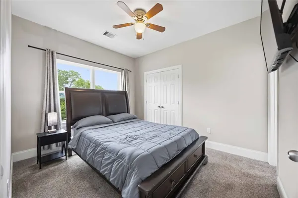 a bedroom with a bed a window and a flat screen tv