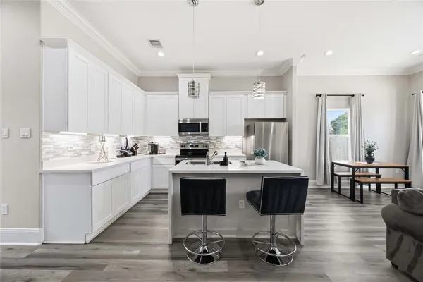 a kitchen with kitchen island stainless steel appliances a dining table and chairs