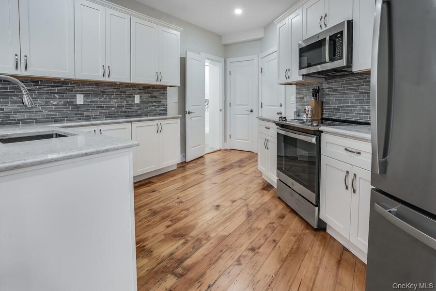 16 South Division Street, Unit 2B Peekskill, NY 10566 - Photo 2 of 8 a kitchen with granite countertop a stove top oven and cabinets