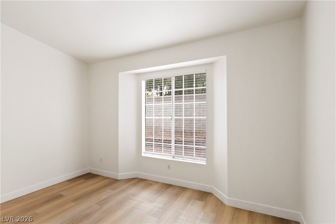 1134 Evening Ridge Street Henderson, NV 89052 - Photo 20 of 35 A well-lit room offers clean lines and durable wood flooring, complemented by a large window with privacy blinds.