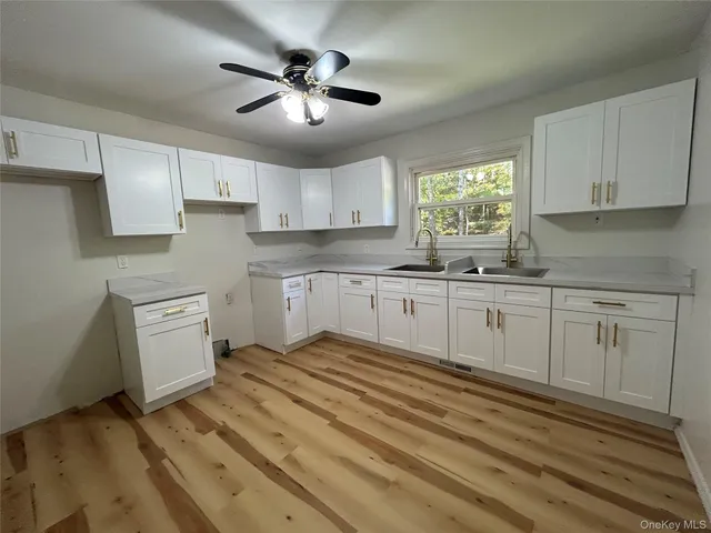a kitchen with white cabinets appliances and a window