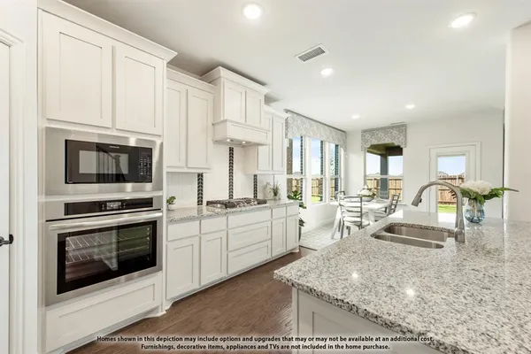 a kitchen with stainless steel appliances granite countertop a stove top oven a sink dishwasher and white cabinets with wooden floor