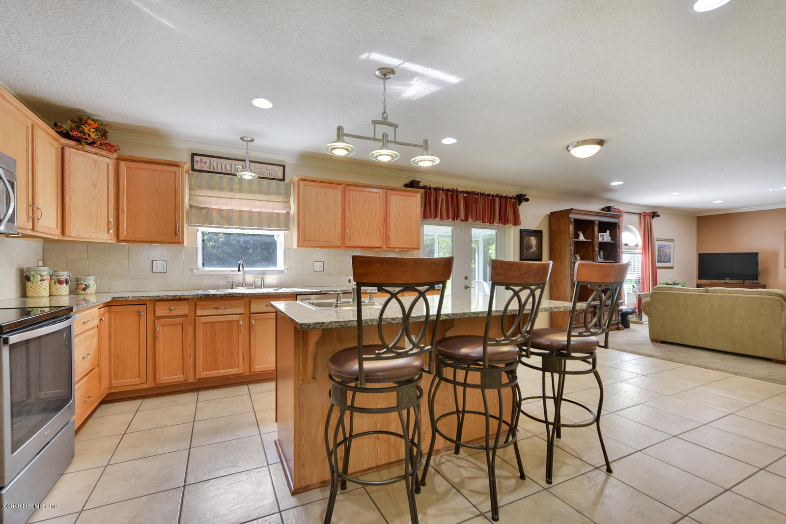 55371 Bear Run Road Callahan, FL 32011 - Photo 9 of 29 a kitchen with stainless steel appliances kitchen island granite countertop a refrigerator a stove top oven and a dining table with wooden floor