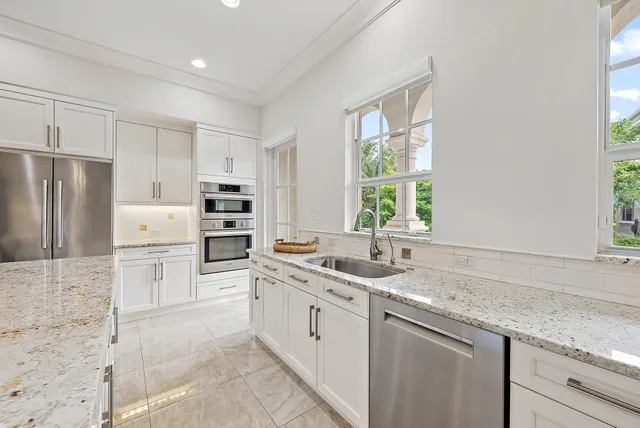 a kitchen with a sink white cabinets and stainless steel appliances