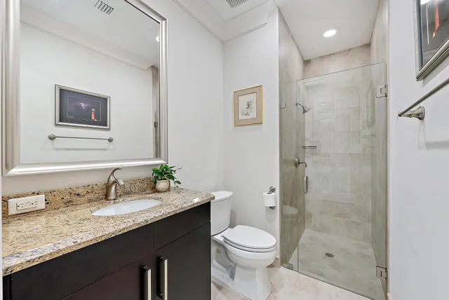 a bathroom with a granite countertop sink a toilet and shower