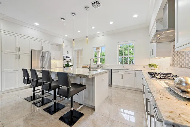 a kitchen with stainless steel appliances kitchen island granite countertop a table chairs and a refrigerator