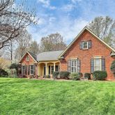 a view of a yard in front of a house with large windows